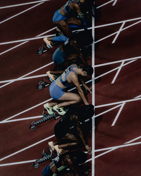 Sprinters crouched in their starting blocks, seen from above