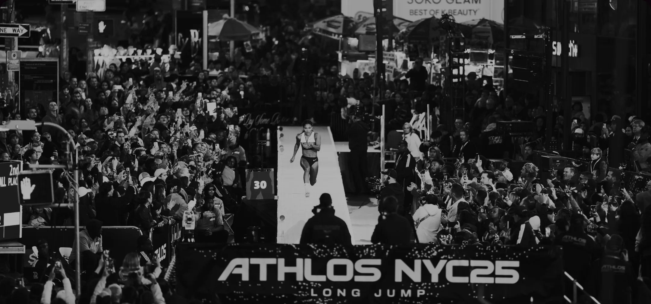 A long jumper sprints down a runway through packed Times Square crowds